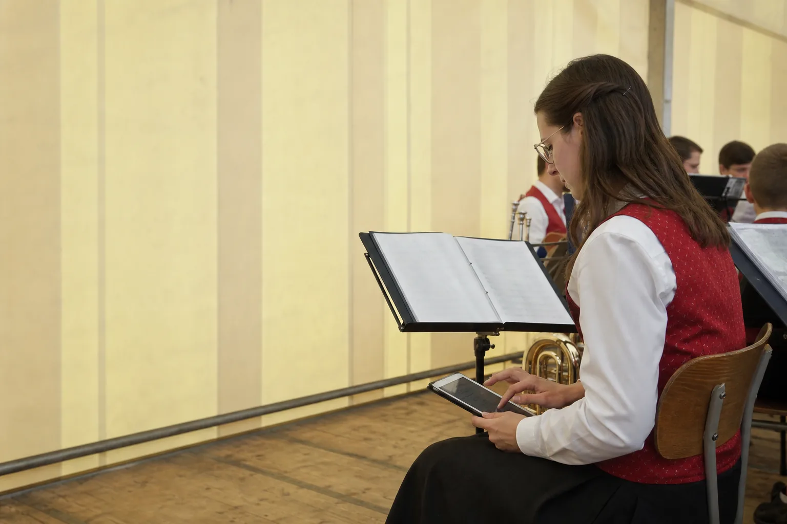Musikerin erfasst während eines Auftritts Titel auf einem Tablet neben dem Notenständer.